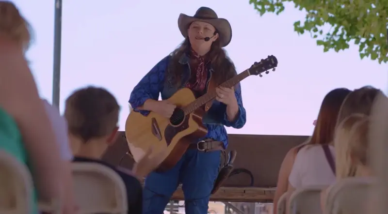Kristen playing live Western music on guitar for a crowd