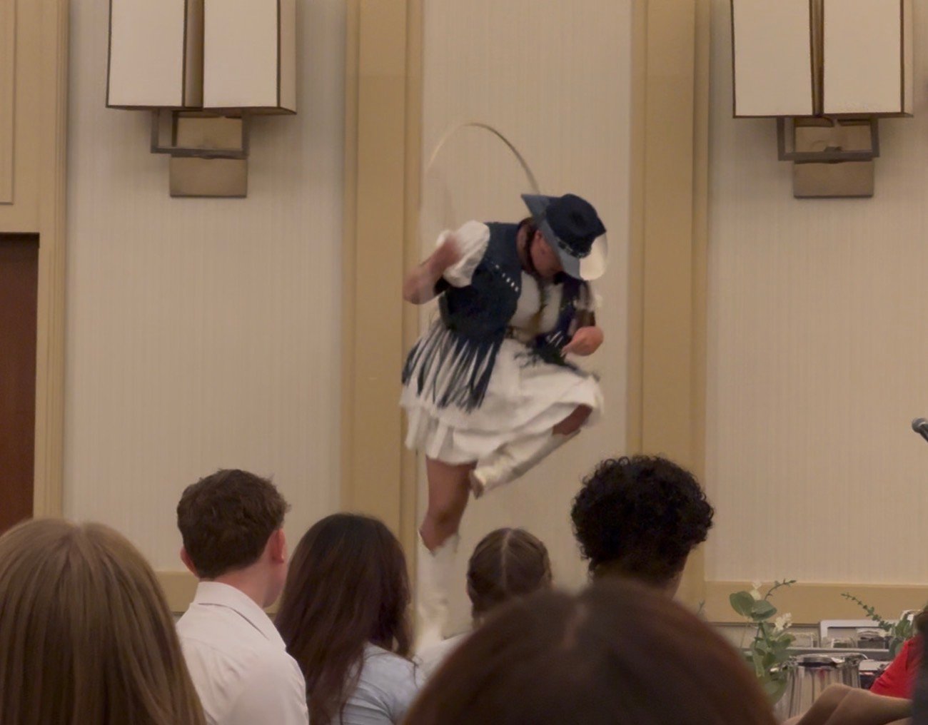 Kristen J. Lloyd jumping through a rope on stage during a resilience keynote